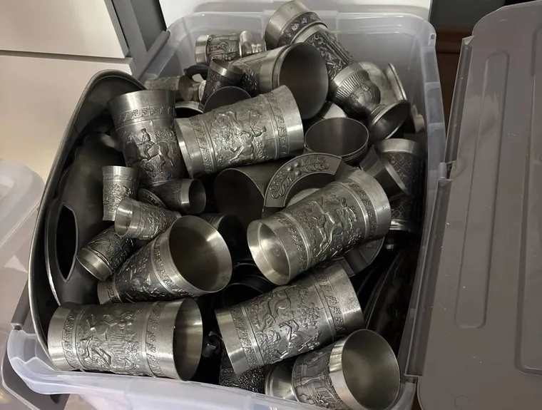 Kiste voller Zinnbecher mit Reliefdekor im Lager